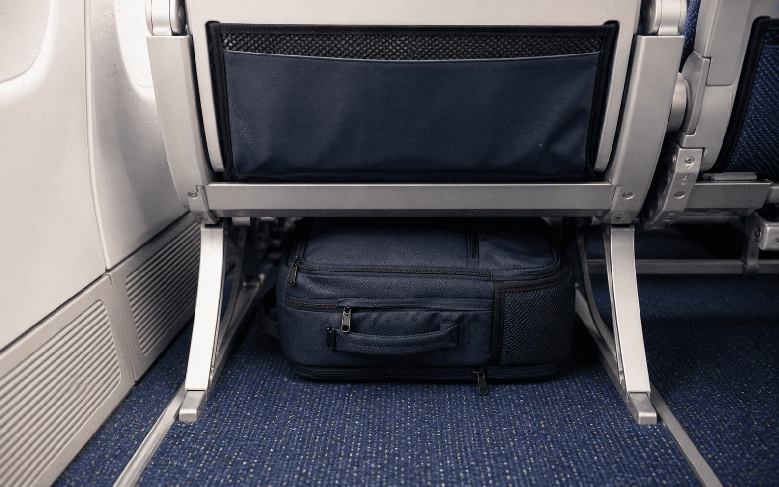 Small personal item bag placed under an airplane seat